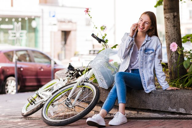 Kobieta rozmawia przez telefon obok roweru