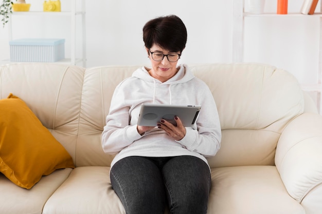 Bezpłatne zdjęcie kobieta siedzi na kanapie z tabletem