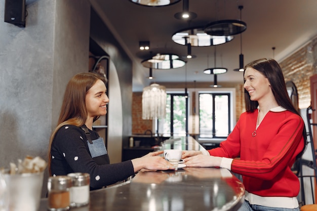 Kobieta siedzi w kawiarni i rozmawia z baristą