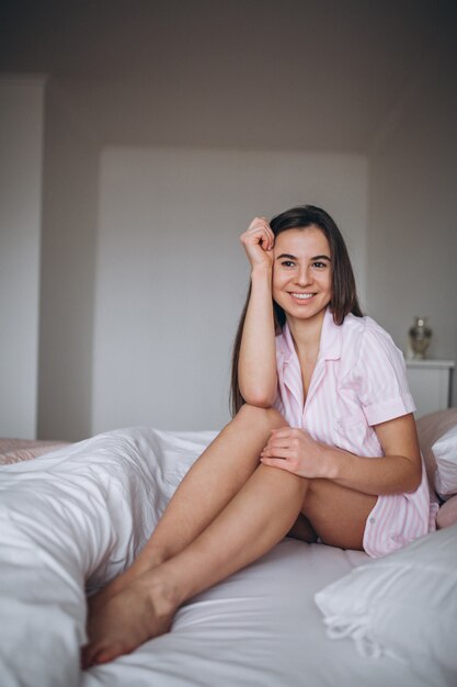 Kobieta siedzi w łóżku w piżamach