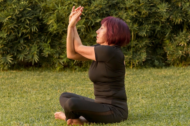 Kobieta siedzi w pozycji jogi i ćwiczeń ramion