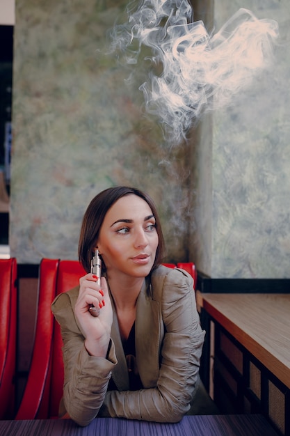 Bezpłatne zdjęcie kobieta siedzi z elektronicznym papierosem