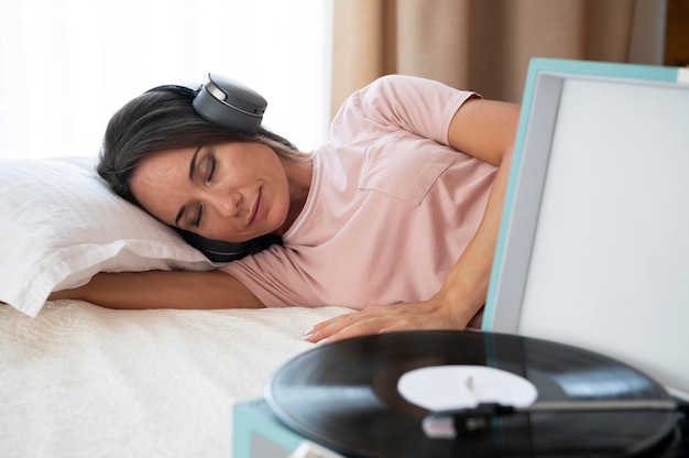 Kobieta słucha muzyki przez słuchawki w domu