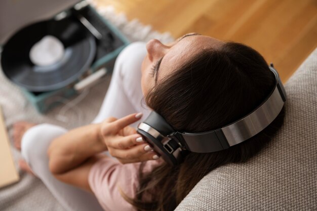 Kobieta słucha muzyki przez słuchawki w domu
