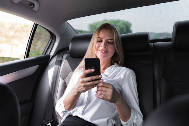 Kobieta SMS-y na tylnym siedzeniu samochodu