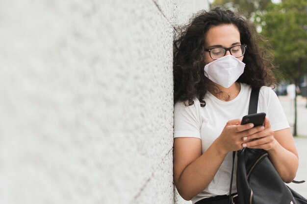 Kobieta sprawdza jej telefon z kopii przestrzenią z medyczną maską