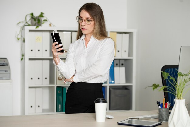 Kobieta sprawdzająca swój telefon w pracy