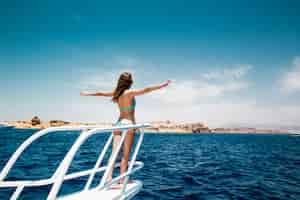 Bezpłatne zdjęcie kobieta stojąca na dziobie jachtu w słoneczny letni dzień, wiatr rozwijający włosy,