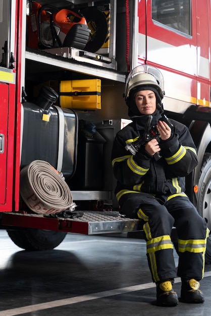 Kobieta strażak na stacji wyposażona w kombinezon i hełm ochronny