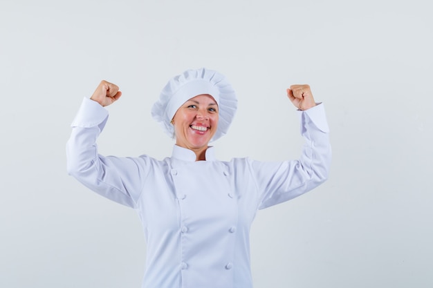 kobieta szef kuchni pokazując gest zwycięzcy w białym mundurze i wyglądający na szczęśliwego