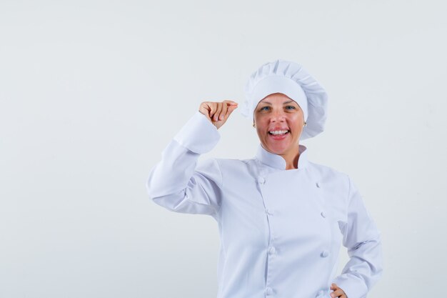 kobieta szef kuchni pozowanie, trzymając coś w białym mundurze i patrząc wesoło