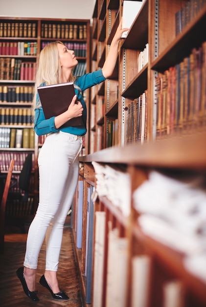 Kobieta szuka książki w bibliotece