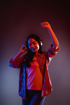 Kobieta tańczy podczas słuchania muzyki przez słuchawki w ciemnym pokoju