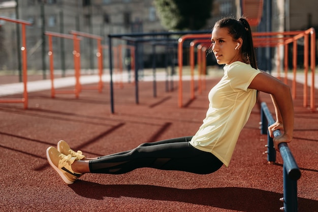 Kobieta trenująca biceps na drążku równoległym na boisku sportowym