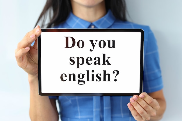 Kobieta trzyma cyfrowy tablet z napisem, czy mówisz po angielsku z bliska, ucząc się zagranicznych
