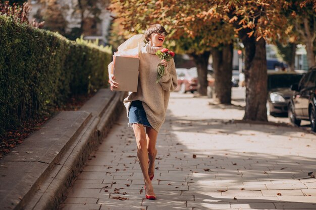 Kobieta trzyma dużą paczkę i idzie ulicą