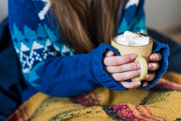 Kobieta trzyma filiżankę z napojem i marshmallows