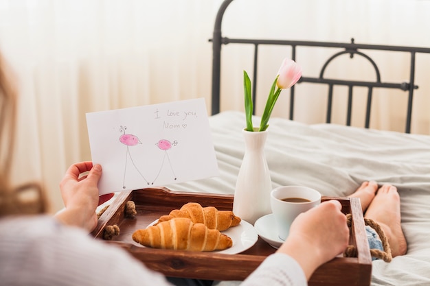 Kobieta trzyma kartkę z życzeniami z kocham cię mama napis