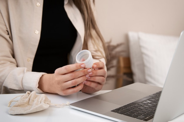 Kobieta trzyma kubek menstruacyjny widok z boku