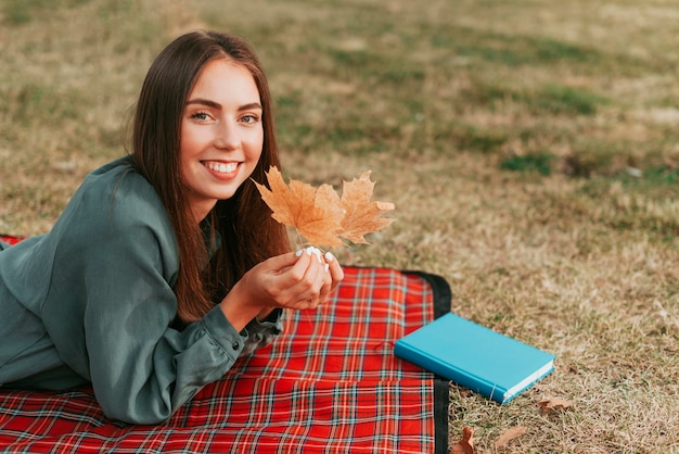 Kobieta trzyma liście na koc piknikowy