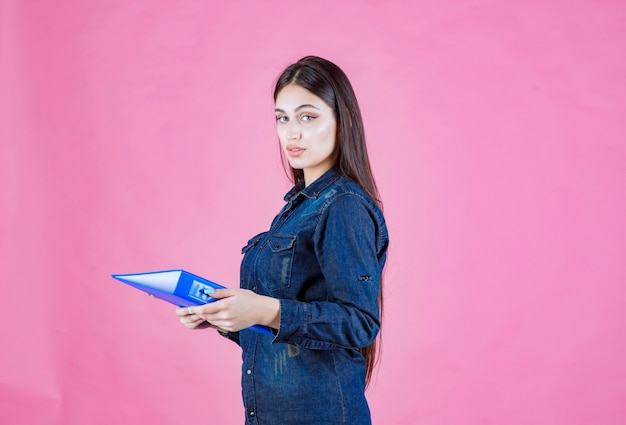 Kobieta trzyma niebieski folder z pewnością siebie