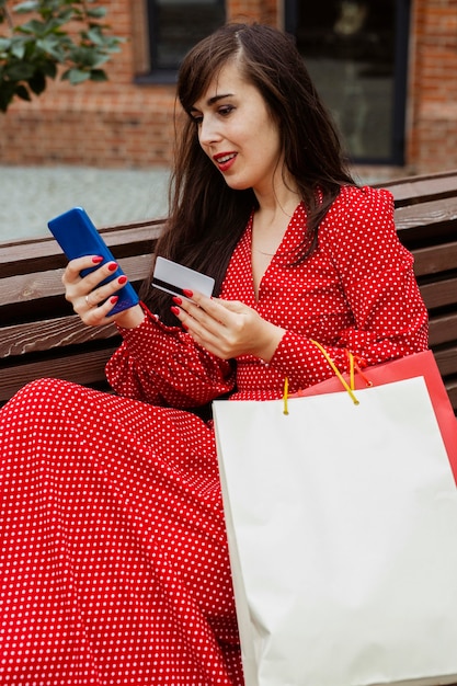 Bezpłatne zdjęcie kobieta trzyma smartfon i kartę kredytową zakupy online podczas sprzedaży