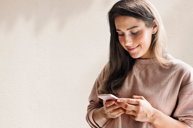 Bezpłatne zdjęcie kobieta trzyma tło smartfona w nowych normalnych zremiksowanych mediach z cieniem liści