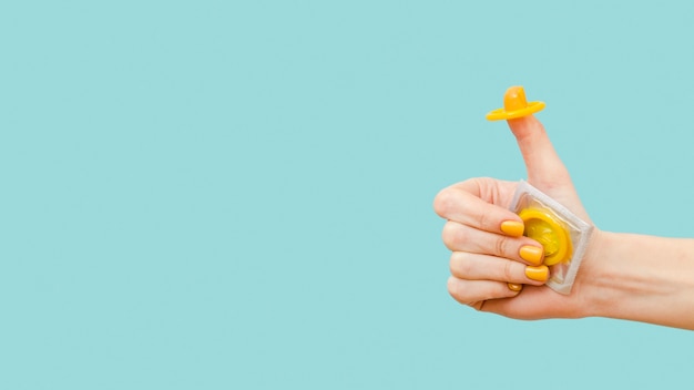 Kobieta trzyma żółtą prezerwatywę na jej palcu