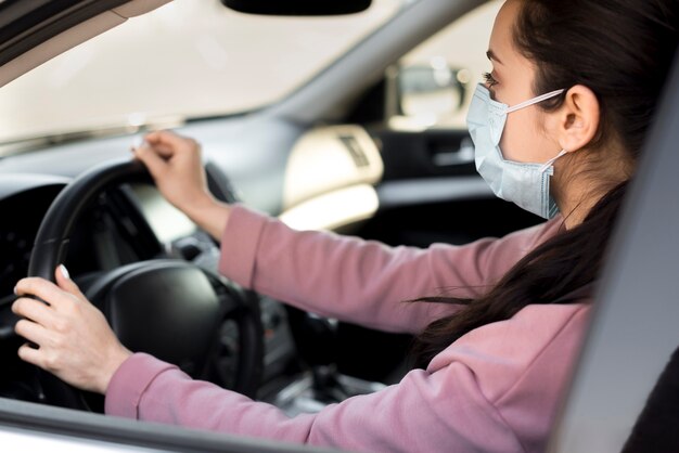 Kobieta ubrana maska wewnątrz własnego samochodu