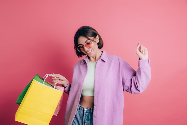Kobieta ubrana na co dzień sweter na tle szczęśliwy korzystających z zakupów trzymając kolorowe torby na sobie letnie okulary przeciwsłoneczne