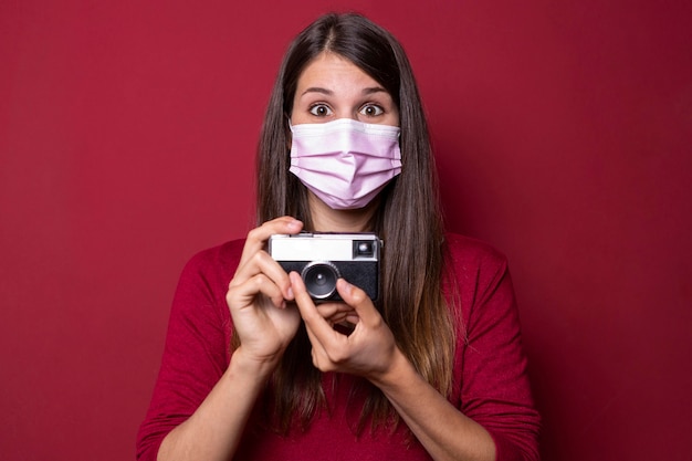 Bezpłatne zdjęcie kobieta ubrana w maskę i trzymając aparat