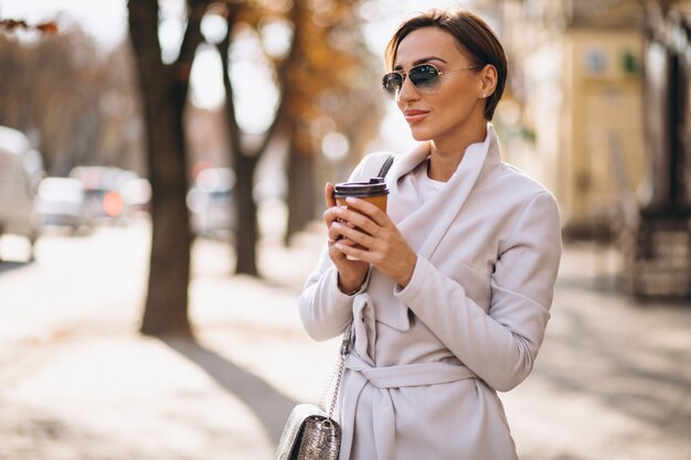 Kobieta ubrana w płaszcz i picia kawy