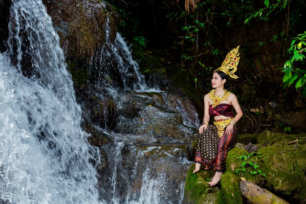 Kobieta ubrana w starożytną tajską sukienkę przy wodospadzie.
