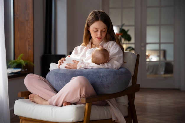 Kobieta używająca poduszki do karmienia w domu dla noworodka