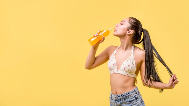 Kobieta w beachwear pozyci i pić soku pomarańczowym