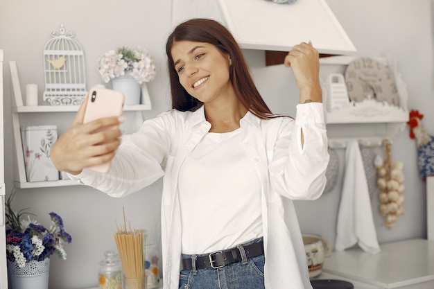 Bezpłatne zdjęcie kobieta w białej koszuli stojący w kuchni i co selfie