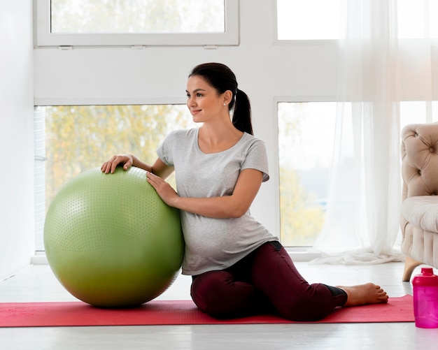 Kobieta w ciąży ćwiczy z zieloną piłkę fitness