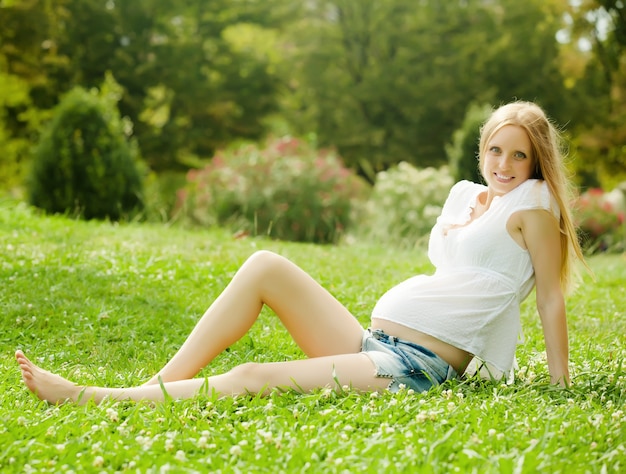 kobieta w ciąży siedzi na trawie