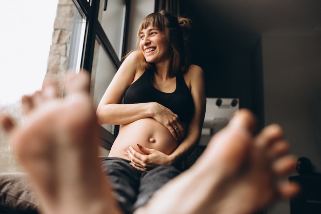 Kobieta w ciąży siedzi przy oknie