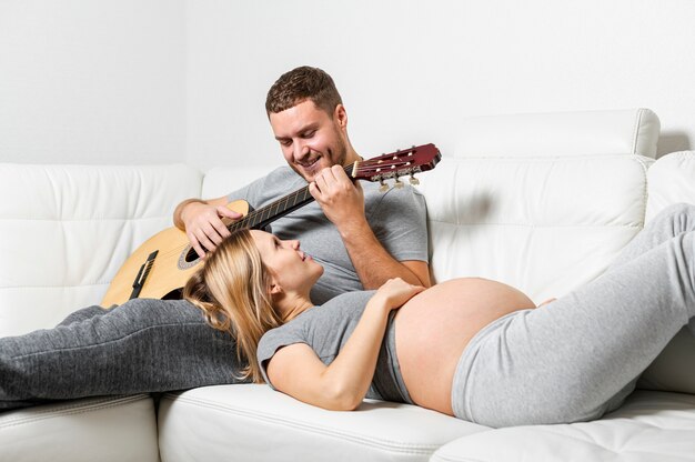 Kobieta w ciąży słucha jej mąż gra na gitarze