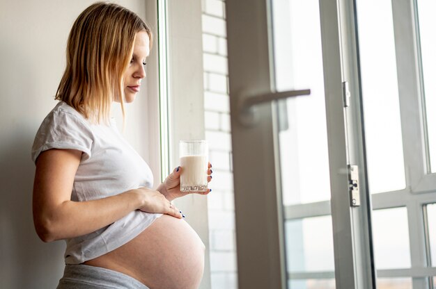 Kobieta w ciąży trzyma szklankę mleka
