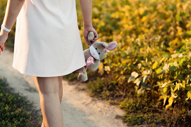 Kobieta w ciąży w różowej sukience trzyma szary królik w jej rękę przetargu