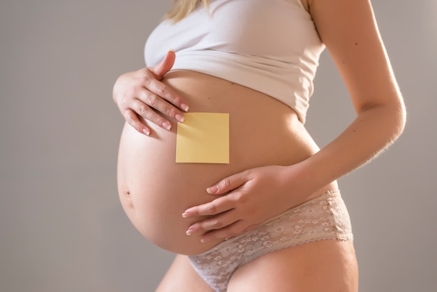 Kobieta w ciąży z notatnikiem na jej brzuchu