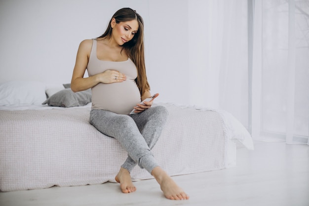 Kobieta w ciąży ze zdjęciem USG siedząca na łóżku