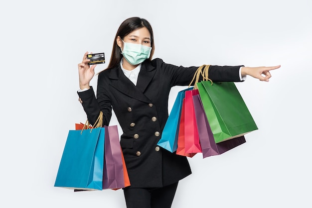 Kobieta w ciemności w masce chodzi na zakupy, nosi karty kredytowe i mnóstwo toreb