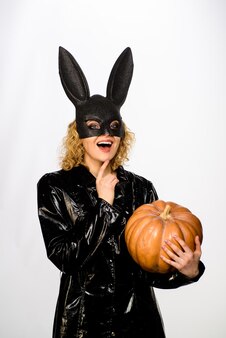 Kobieta w czarnej masce króliczka z dynią uśmiechnięta kobieta w halloweenowym kostiumie króliczka październik seksowna dziewczyna w