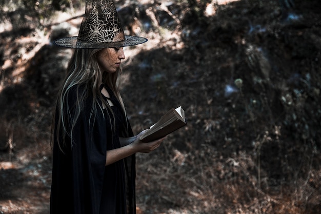 Bezpłatne zdjęcie kobieta w czarownica kostium czytanie książki