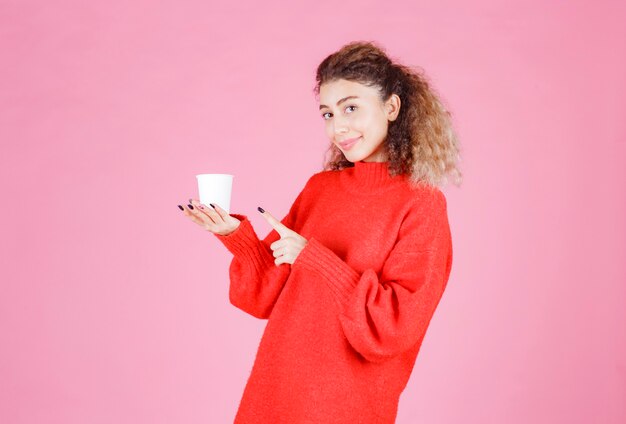 kobieta w czerwonej koszuli trzyma filiżankę kawy jednorazowego użytku.