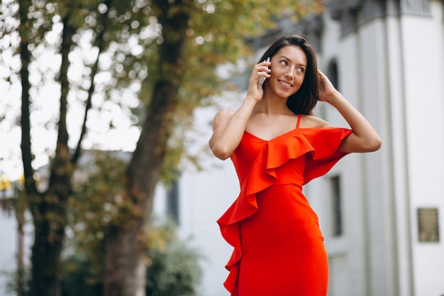 Kobieta w czerwonej sukience za pomocą telefonu