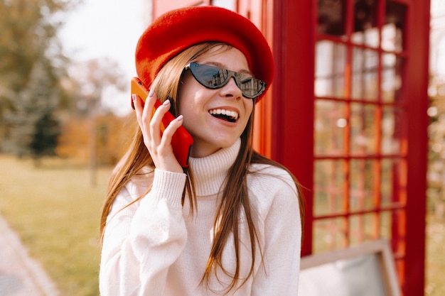 Bezpłatne zdjęcie kobieta w czerwonym berecie z rozmową przez telefon na ulicy